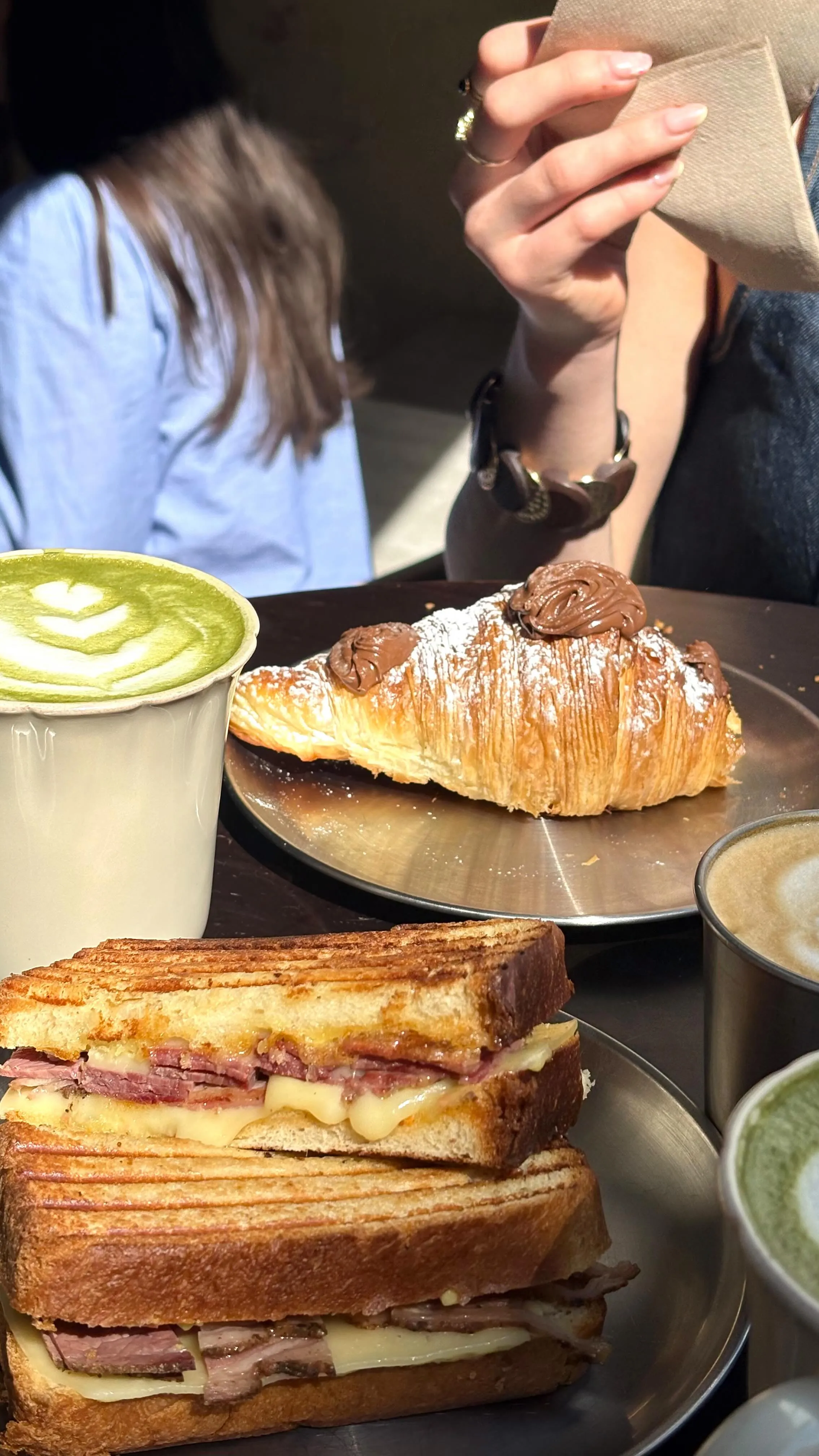Mesa con croissant, sándwich y matcha